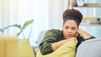 Thinking, tired and black woman on the sofa with depression, anxiety or sad from a breakup. House, young and an African girl on the living room couch with an idea after job fail, mistake or divorce