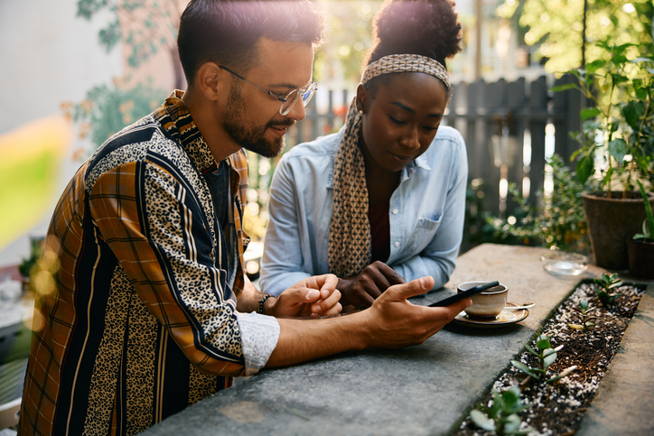 Young multiracial couple using mobile phone while sitting in a cafe,