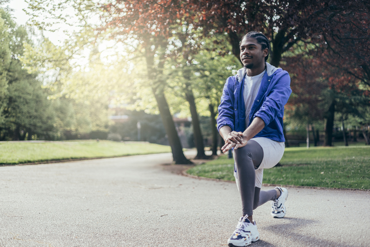 Portrait of fit young african american man doing stretching legs in park