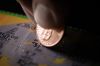 Extreme Macro Close-Up of a Caucasian Person's Hand Holding a Penny and Scraping a Scratch-Off Lottery Ticket