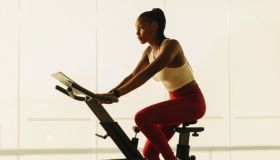 Healthy home workout: Sporty black female exercising on stationary bike