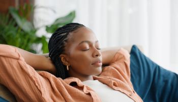Black woman, relax and sleeping on sofa with dream of future investment in home or living room. Person with eyes closed on her couch or lounge for break, peace and security of house, mortgage or rent
