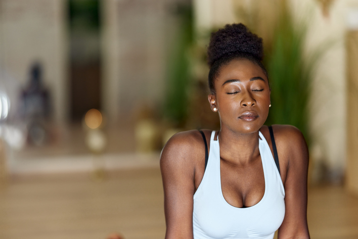 Relaxed black athlete exercising breathing in a health club.