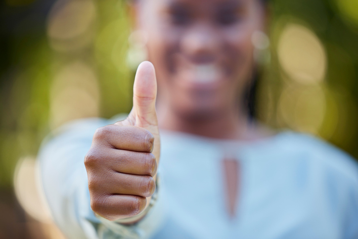 Hand, closeup and thumbs up by black woman showing yes, recommendation or thank you on bokeh background. Zoom, hands and emoji sign, symbol or icon by corporate employee in agreement, support or vote