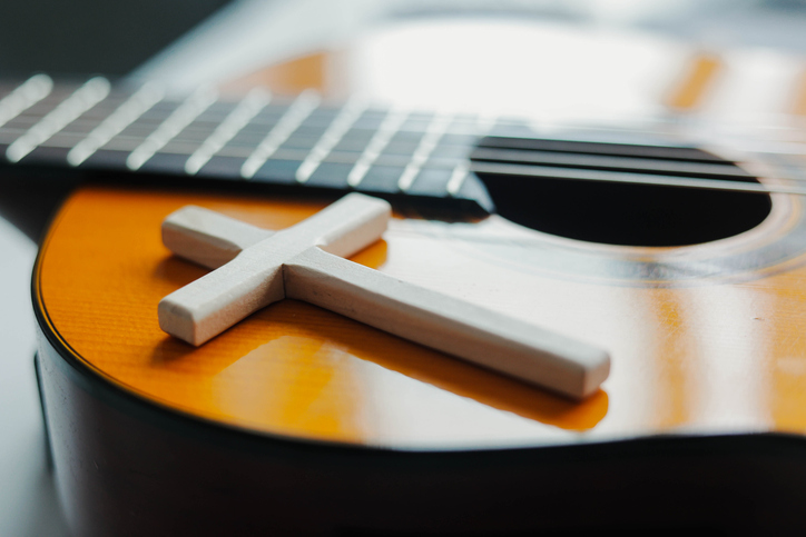 Acoustic guitar with wooden cross on the table close up. Worship God. Christian music.