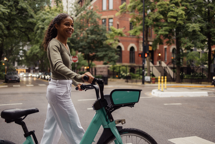 Stigma of Singleness - Happy African American woman walking with a bike on the street.