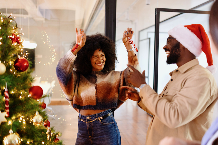 Portrait of a beautiful woman decorating a Christmas tree with her colleagues